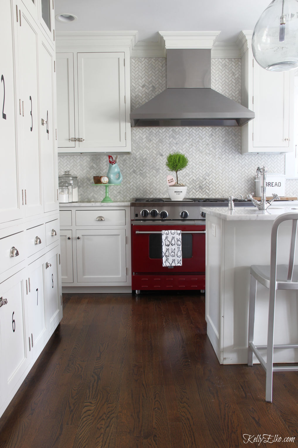 White kitchen with stunning red stove and marble herringbone backsplash kellyelko.com #whitekitchen #redstove #backsplash #farmhousekitchen #cottagekitchen #classickitchen #whitecabinets #kitchendecor #kitchenreno #kellyelko