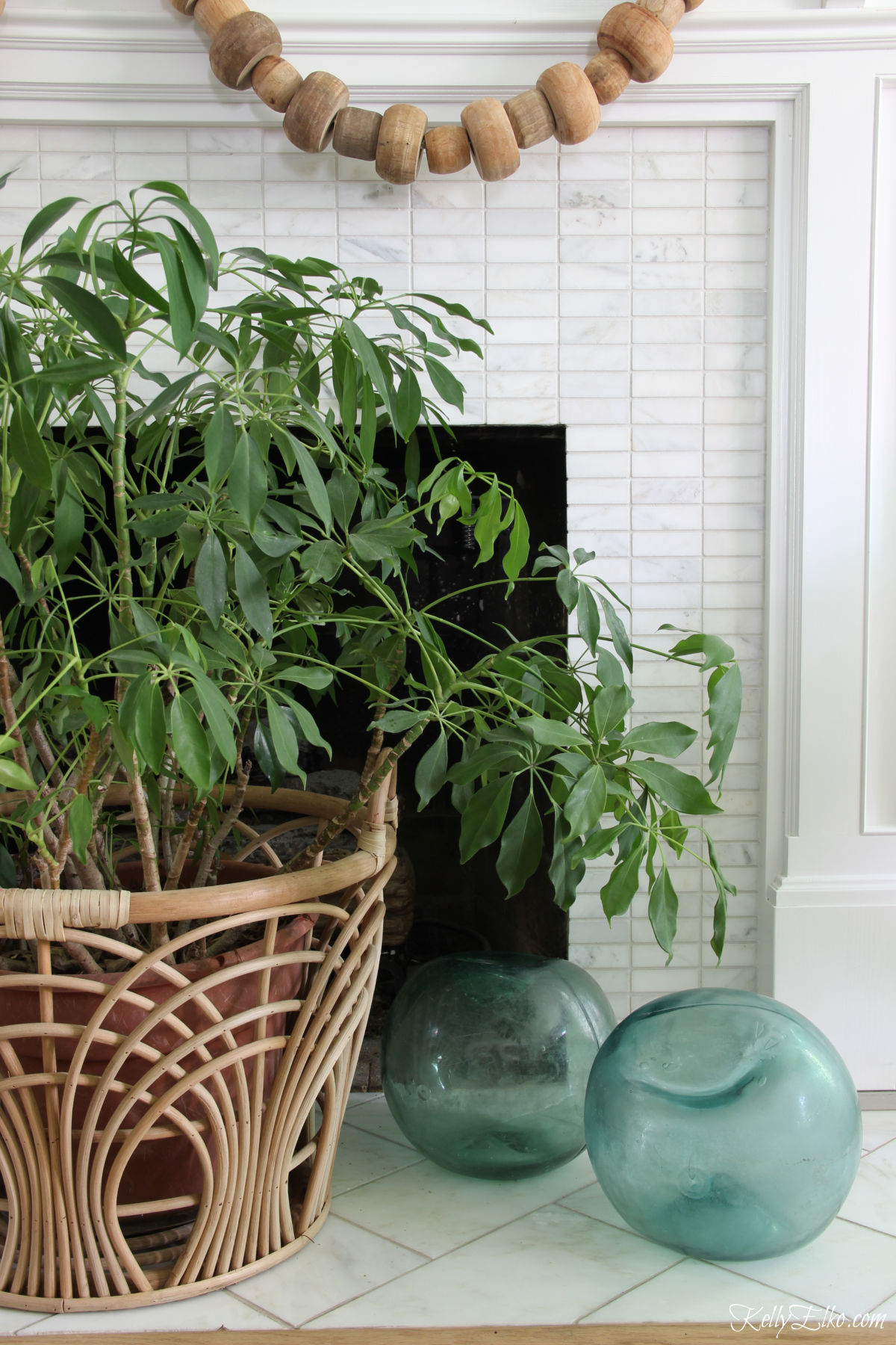 Love the texture of this rattan basket and glass buoys to cover the fireplace hole kellyelko.com #hearth #hearthdecor #bohodecor #coastaldecor #manteldecor #houseplants 