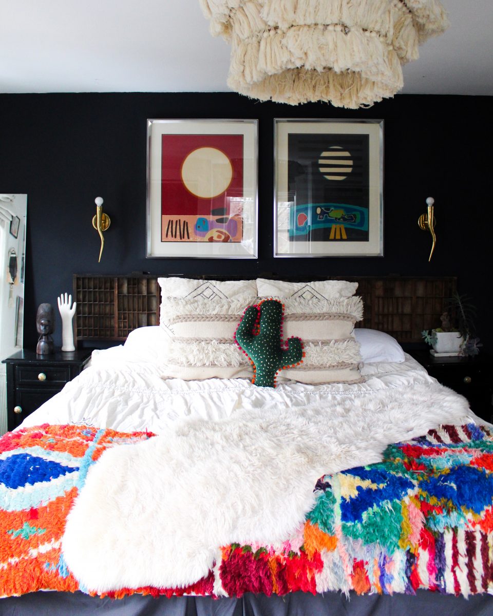 Love the dark black walls in this boho bedroom and the colorful bedding and art kellyelko.com #bedrooms #bedroomdecor #bohobedroom #bohodecor #vintagedecor #macrame #vintagemodern 