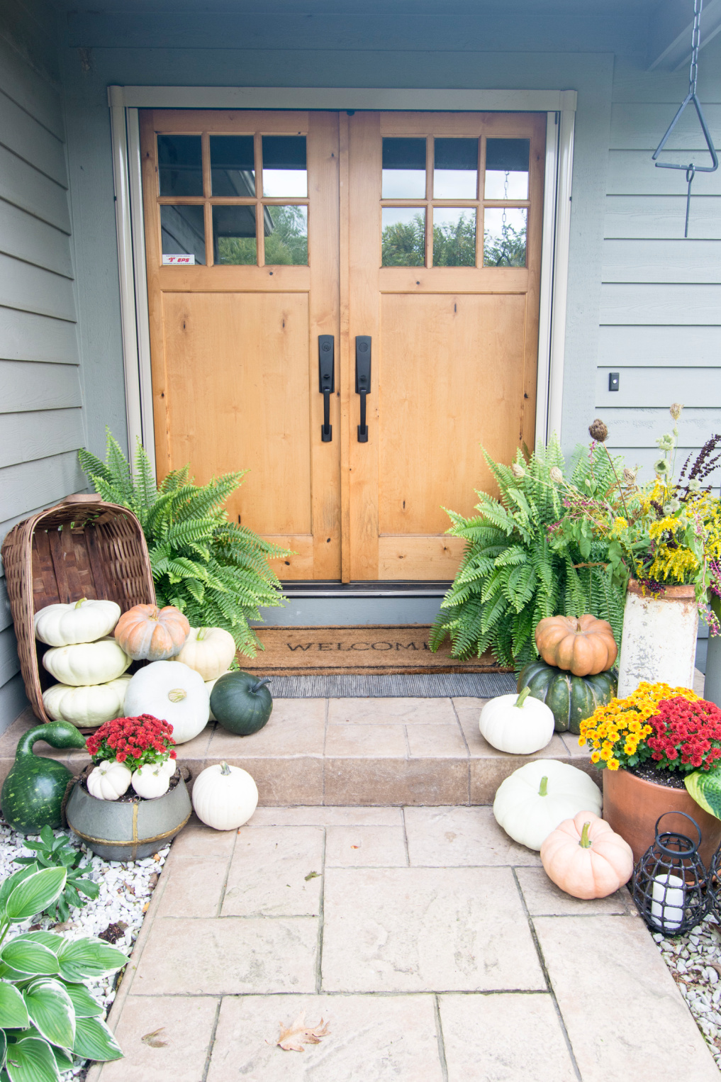 10 Beautiful Fall Porches - love the pumpkins spilling out of the basket kellyelko.com #fall #fallporch #falldecor #falldecorating #pumpkins #curbappeal #autummdecor #autummporch