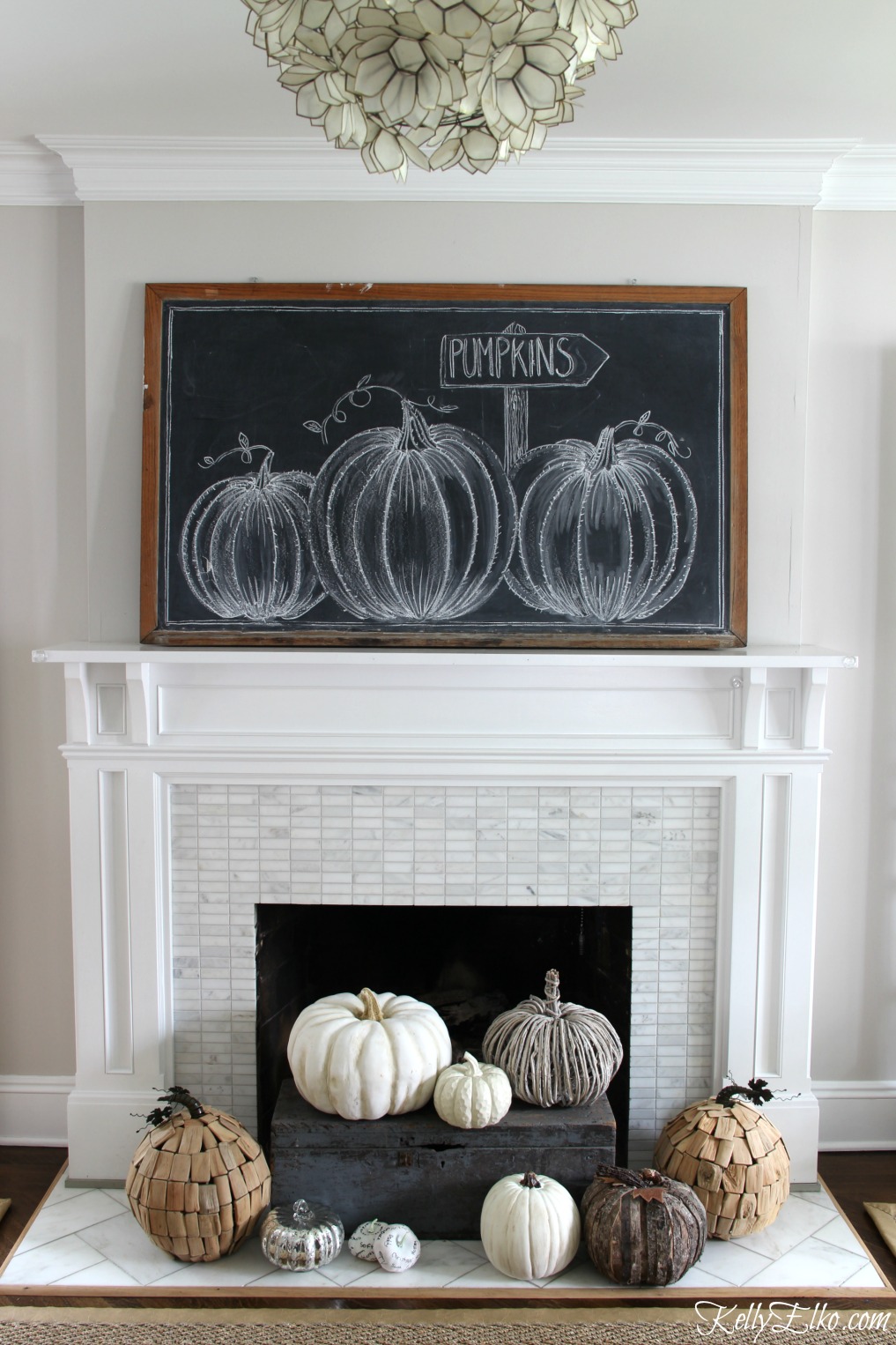 Pumpkin chalkboard art and neutral pumpkins piled in fireplace kellyelko.com