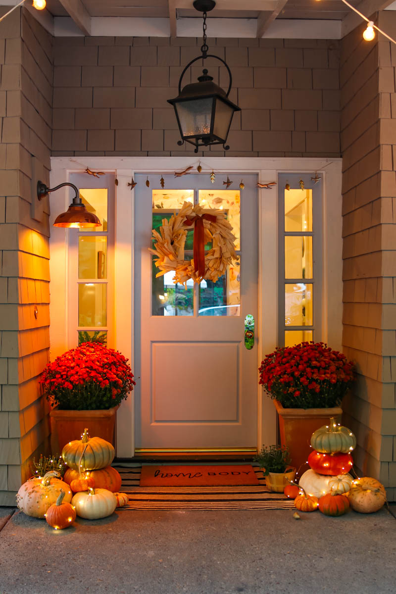 10 Beautiful Fall Porches - love the fairy lights wrapped around the pumpkins kellyelko.com #fall #fallporch #falldecor #falldecorating #mums #pumpkins #fairylights #porch #frontporch #curbappeal #autummdecor #autummporch