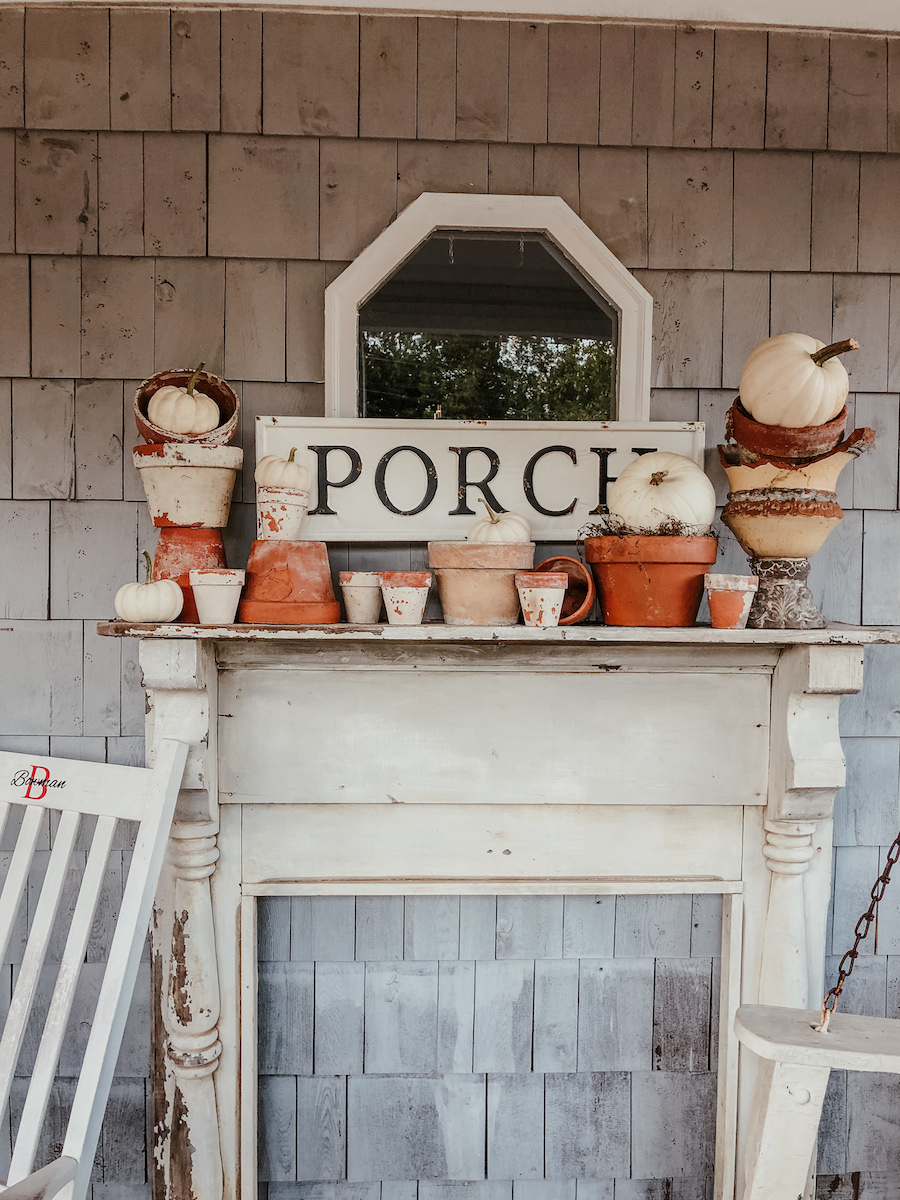 An antique mantel on the front porch is a fun place to decorate for fall with terra cotta pots piled high with pumpkins kellyelko.com #fall #falldecor #farmhousedecor #farmhousestyle #vintagedecor #pumpkins #fallporch #porchdecor #frontporch 