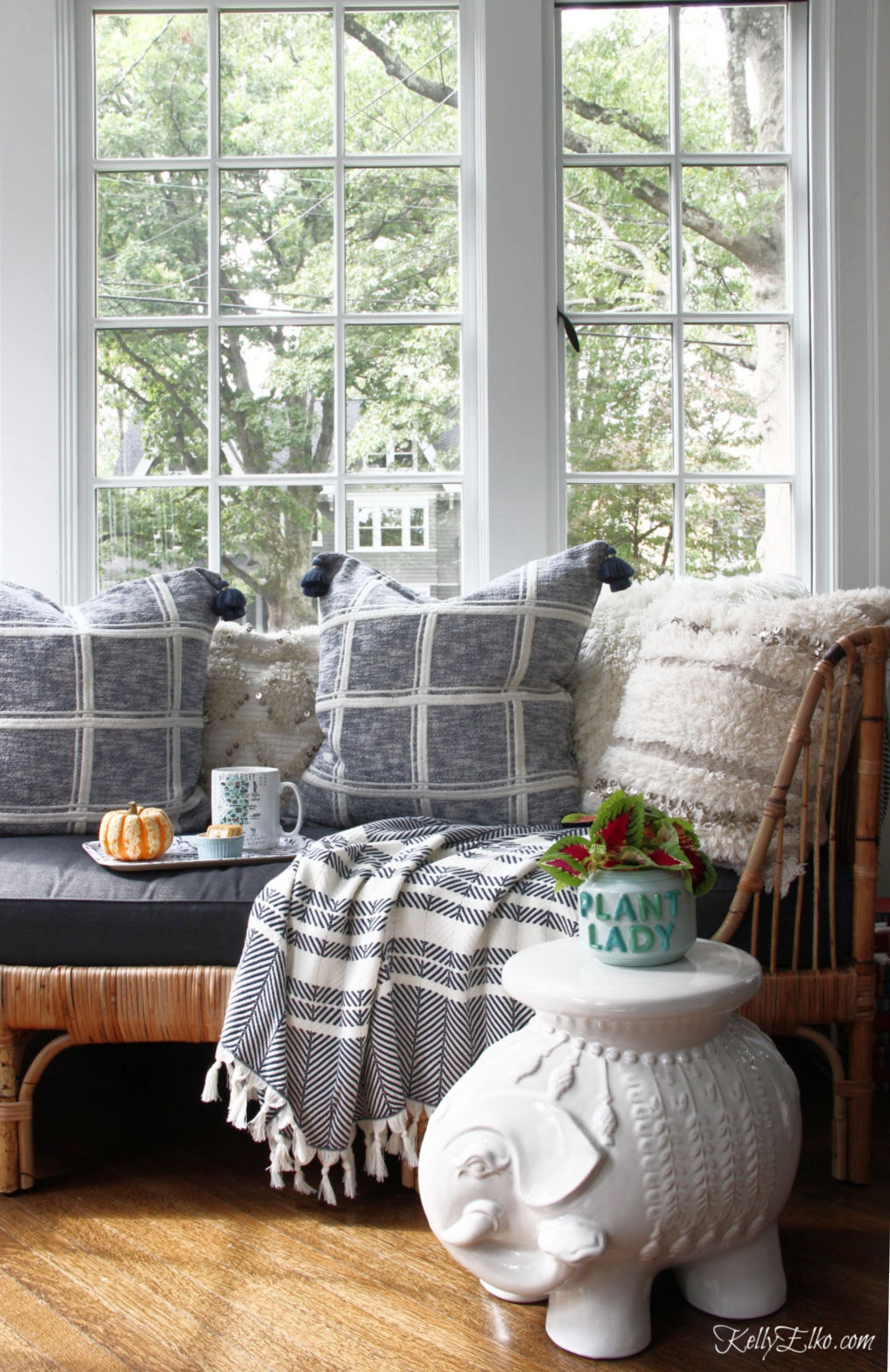 A rattan daybed is the perfect place to pile high with cozy pillows and throws and the ceramic elephant stool is the perfect plant stand kellyelko.com #bohodecor #rattanfurniture #rattan #daybed #sunroomdecor #sunroom #serenaandlily #blueandwhitedecor #plantlady