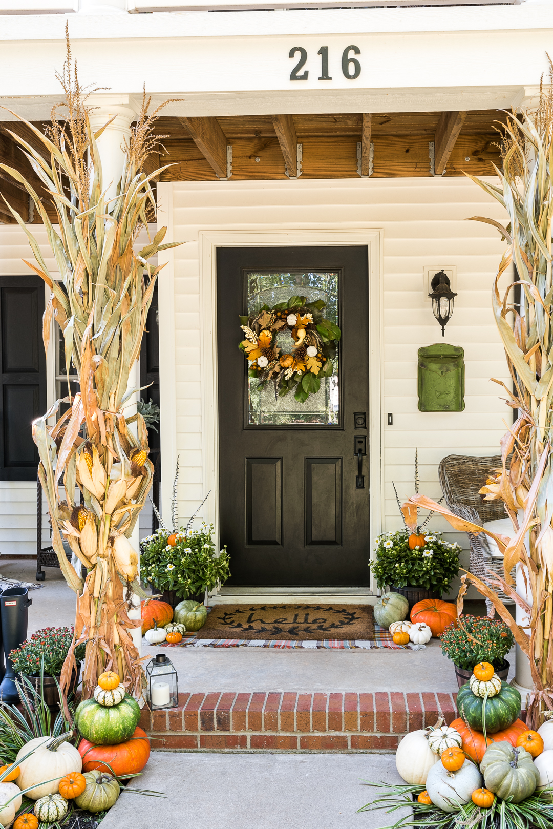 10 Beautiful Fall Porches - love the corn stalks and feathers in the planters kellyelko.com #fall #fallporch #falldecor #falldecorating #mums #pumpkins #fairylights #porch #frontporch #curbappeal #autummdecor #autummporch