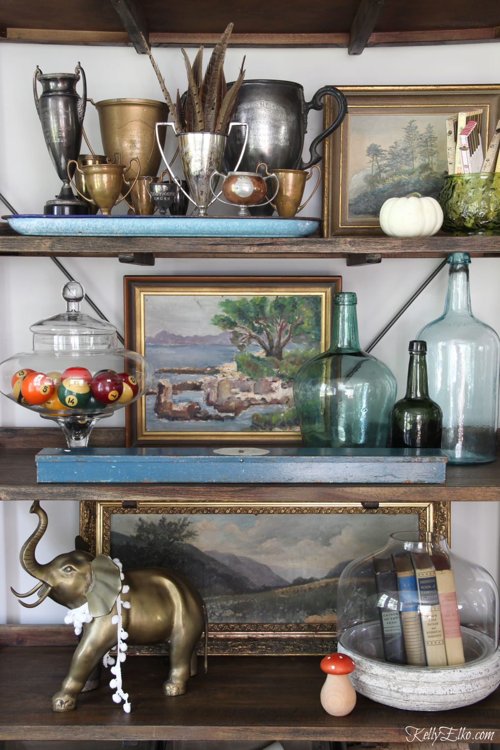 Love this shelf filled with an eclectic assortment of vintage finds including vintage loving cups, paintings and glass jars kellyelko.com #fall #falldecor #falldecorating #shelfstyling #vintagedecor #eclecticdecor #collections #homedecor