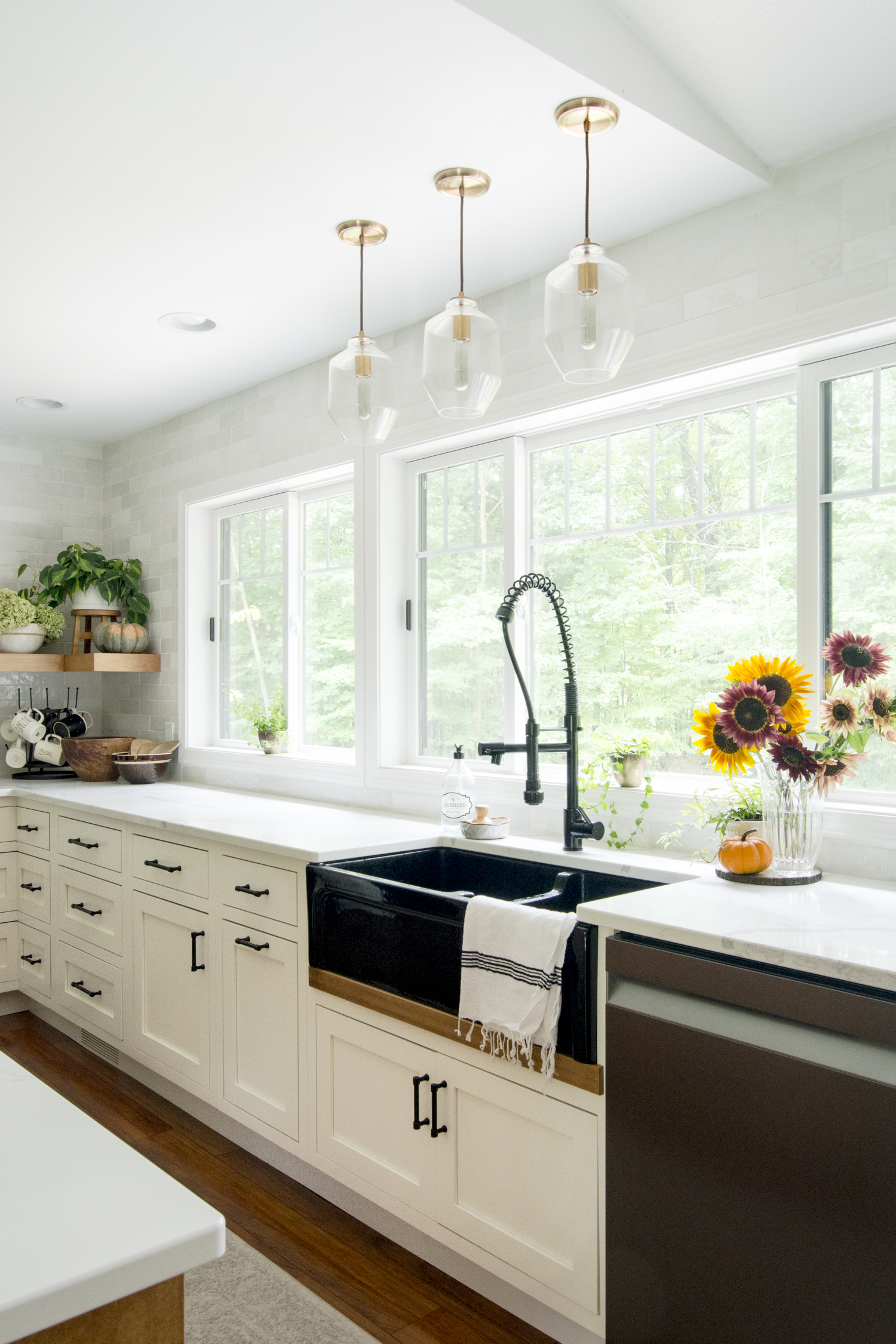 Love the black farmhouse sink and trip of glass pendant lights kellyelko.com #kitchen #kitchenlighting #lighting #farmhousesink #farmhousekitchen #farmhousedecor #whitekitchen #interiordesign 