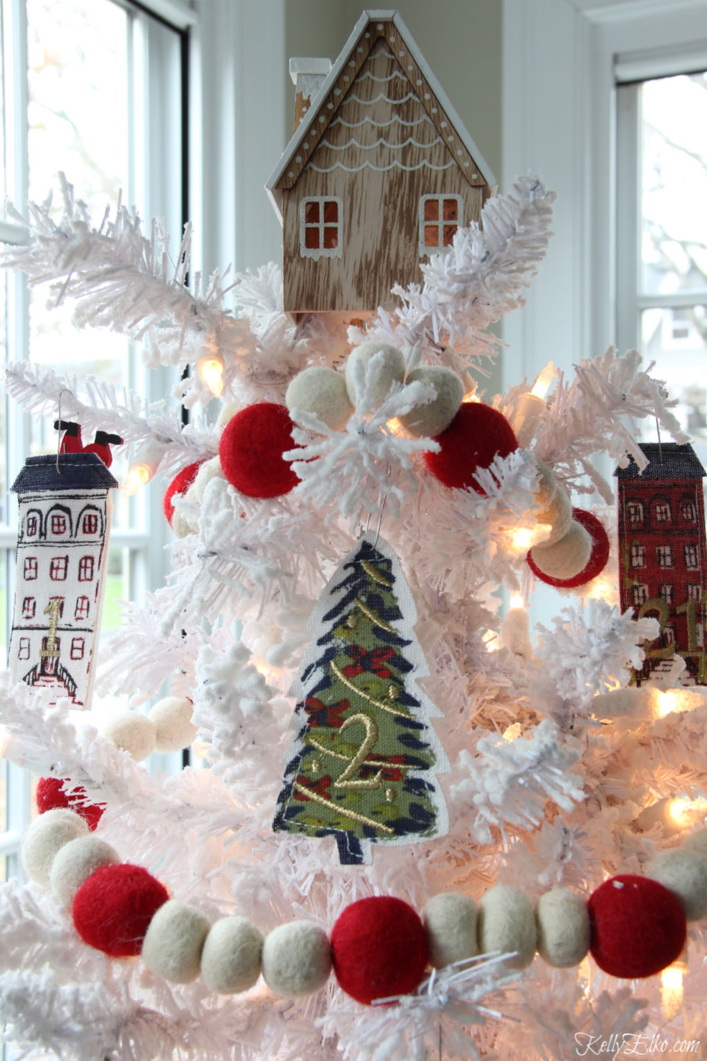Love this advent calendar Christmas tree with tiny fabric houses kellyelko.com #christmas #diychristmas #christmastree #whitechristmastree #whitechristmas #adventcalendar #christmasgarland #kidschristmas #kellyelko