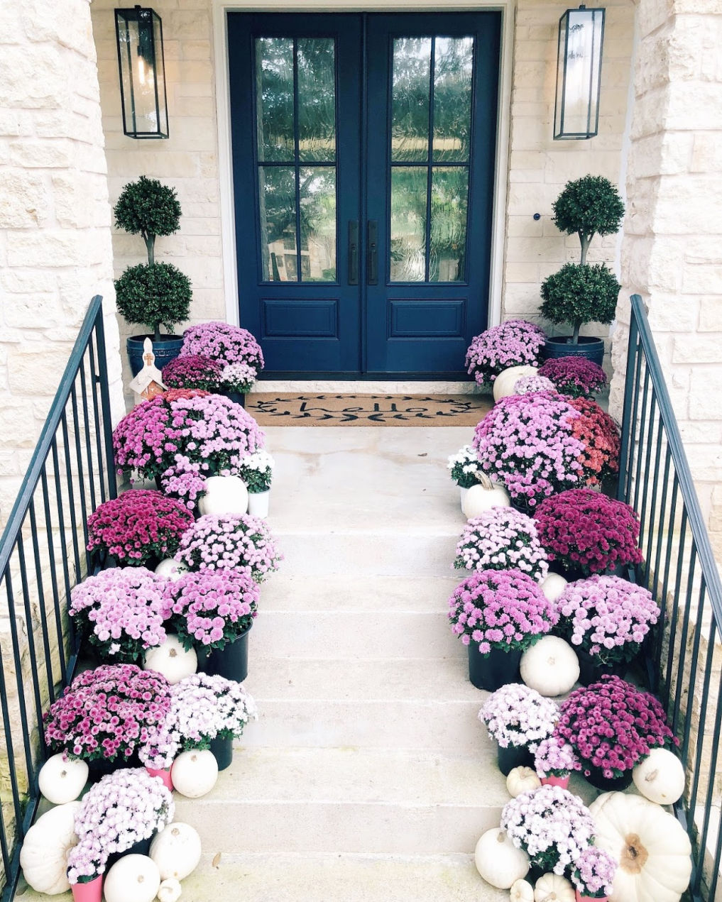 Fall front porch with purple mums and white pumpkins 