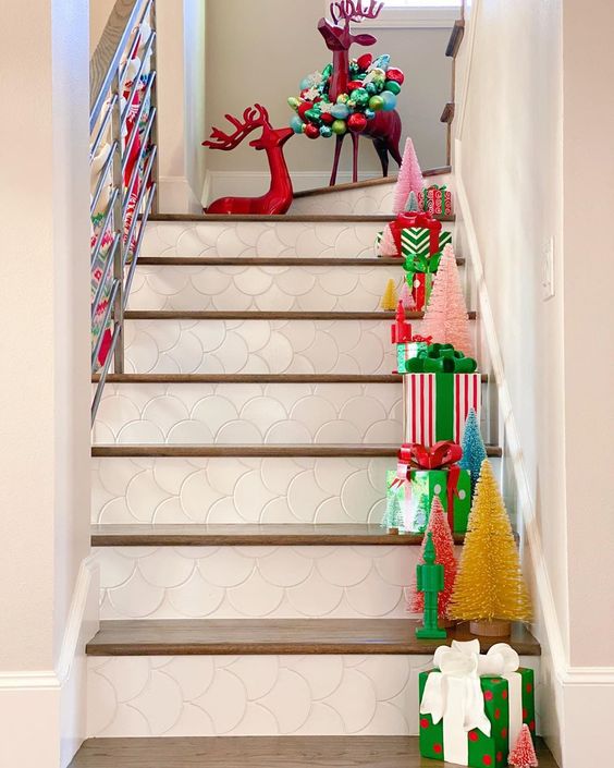 Bottle Brush Tree Ideas - love this staircase filled with colorful trees and gifts #christmasdecor #colorfulchristmas #bottlebrushtrees #christmastrees #christmasstairs 