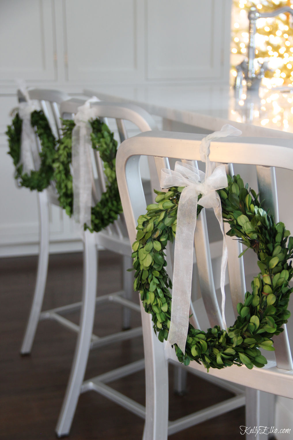 Love this Christmas Home Tour with mini boxwood wreaths on kitchen counter stools kellyelko.com #christmas #christmasdecor #christmasdecorating #christmashome #christmastour #diychristmas #christmasideas #christmasmantel #christmastree #christmasornaments #vintagechristmas #farmhousechristmas #colorfulchristmas #creativechristmas #kellyelko #boxwood #boxwoodwreaths #christmaskitchen 