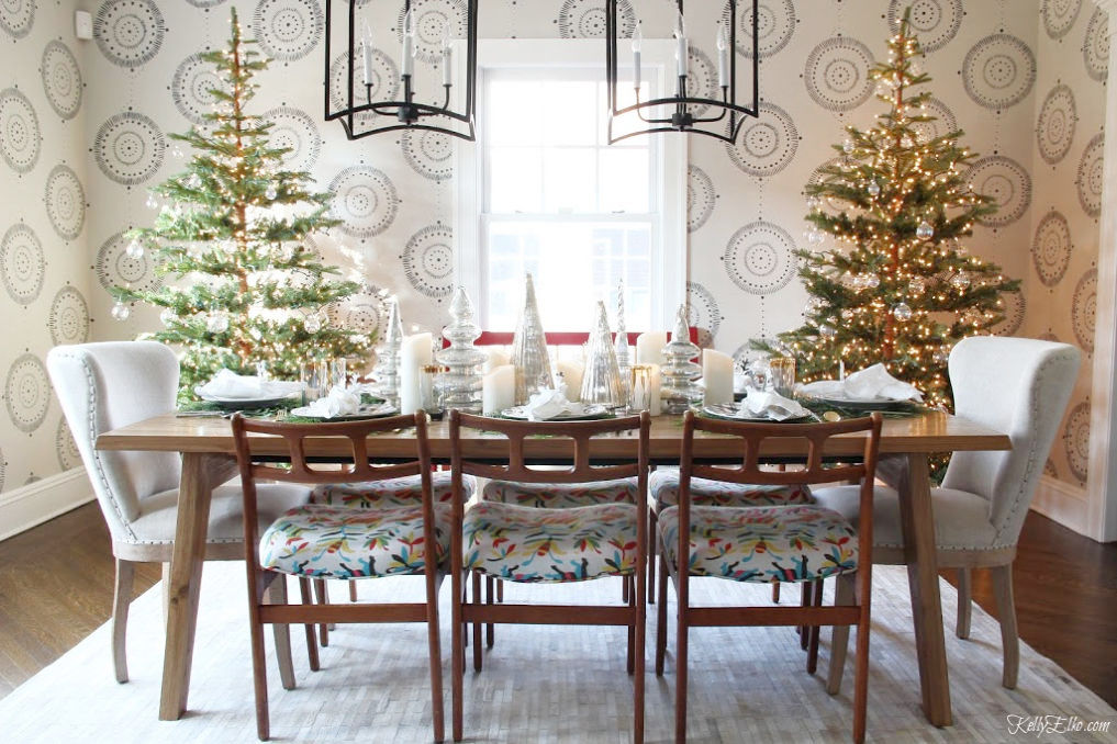 Creative Christmas Home Tour - love this dining room with two Christmas trees in gold and silver kellyelko.com #christmas #christmasdecor #christmasdecorating #christmashome #christmastour #diychristmas #christmasideas #christmasmantel #christmastree #christmasornaments #vintagechristmas #farmhousechristmas #colorfulchristmas #creativechristmas #kellyelko #diningroom #christmasdiningroom #sparsechristmastrees #otomi #farmhousestyle #wallmural 