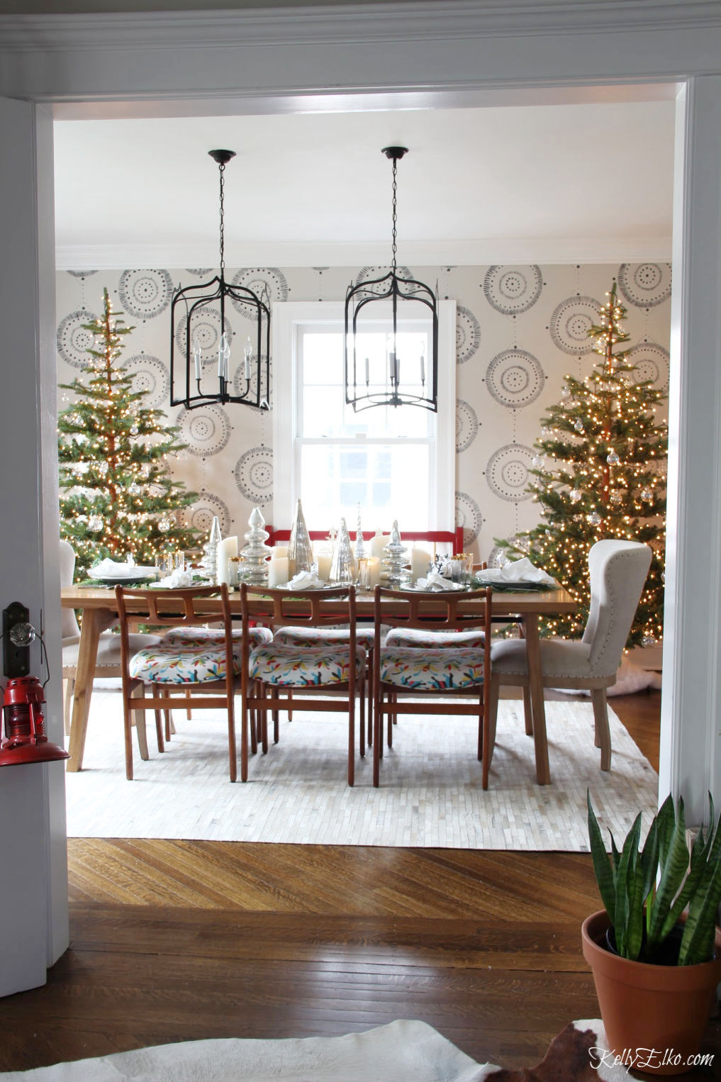 Beautiful Christmas Home Tour - love the pair of sparse Christmas trees in the dining room covered in clear ornaments kellyelko.com #christmas #christmasdecor #christmasdecorating #christmashome #christmastour #diychristmas #christmasideas #christmasmantel #christmastree #christmasornaments #vintagechristmas #farmhousechristmas #colorfulchristmas #creativechristmas #kellyelko #christmasdiningroom #diningroom #lighting #chandeliers 