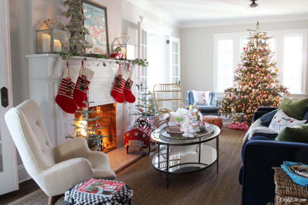 Beautiful Christmas Home Tour - love this whimsical mantel with colorful pom pom stockings and tree covered in vintage ornaments kellyelko.com #christmas #christmasdecor #christmasdecorating #christmashome #christmastour #diychristmas #christmasideas #christmasmantel #christmastree #christmasornaments #vintagechristmas #farmhousechristmas #colorfulchristmas #creativechristmas #kellyelko #christmaslivingroom #shinybrites #vintageornaments 