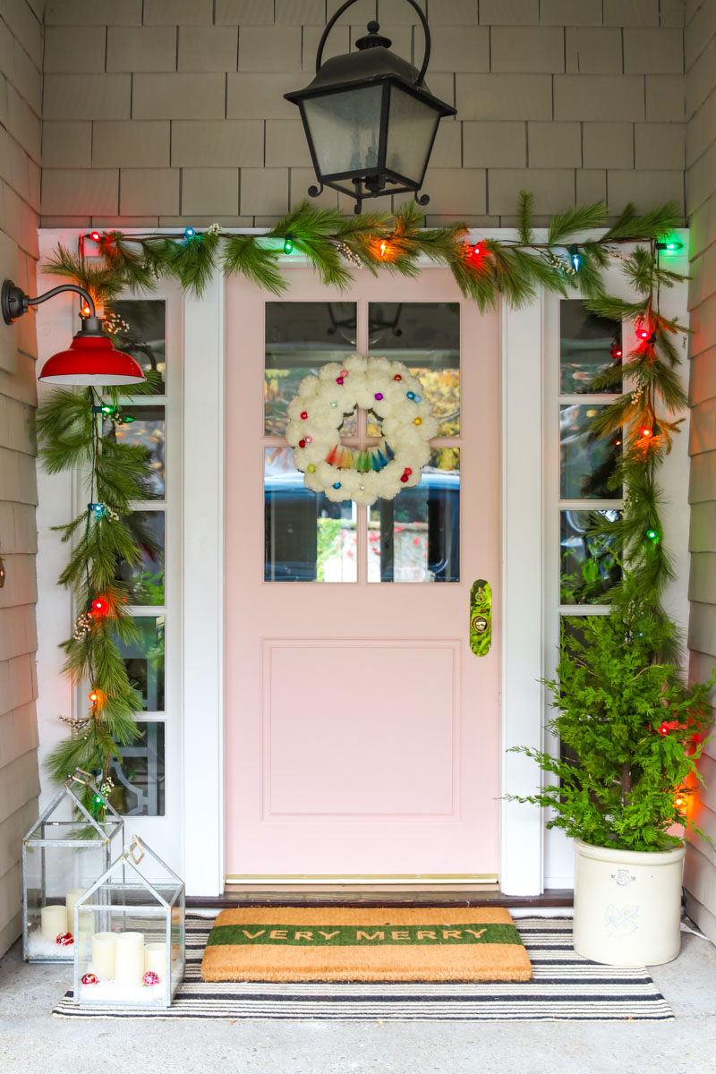 Festive and colorful Christmas porch with pink door #christmas #christmasdecor #christmasporch #pinkdoor #christmasgarland #christmaslights 