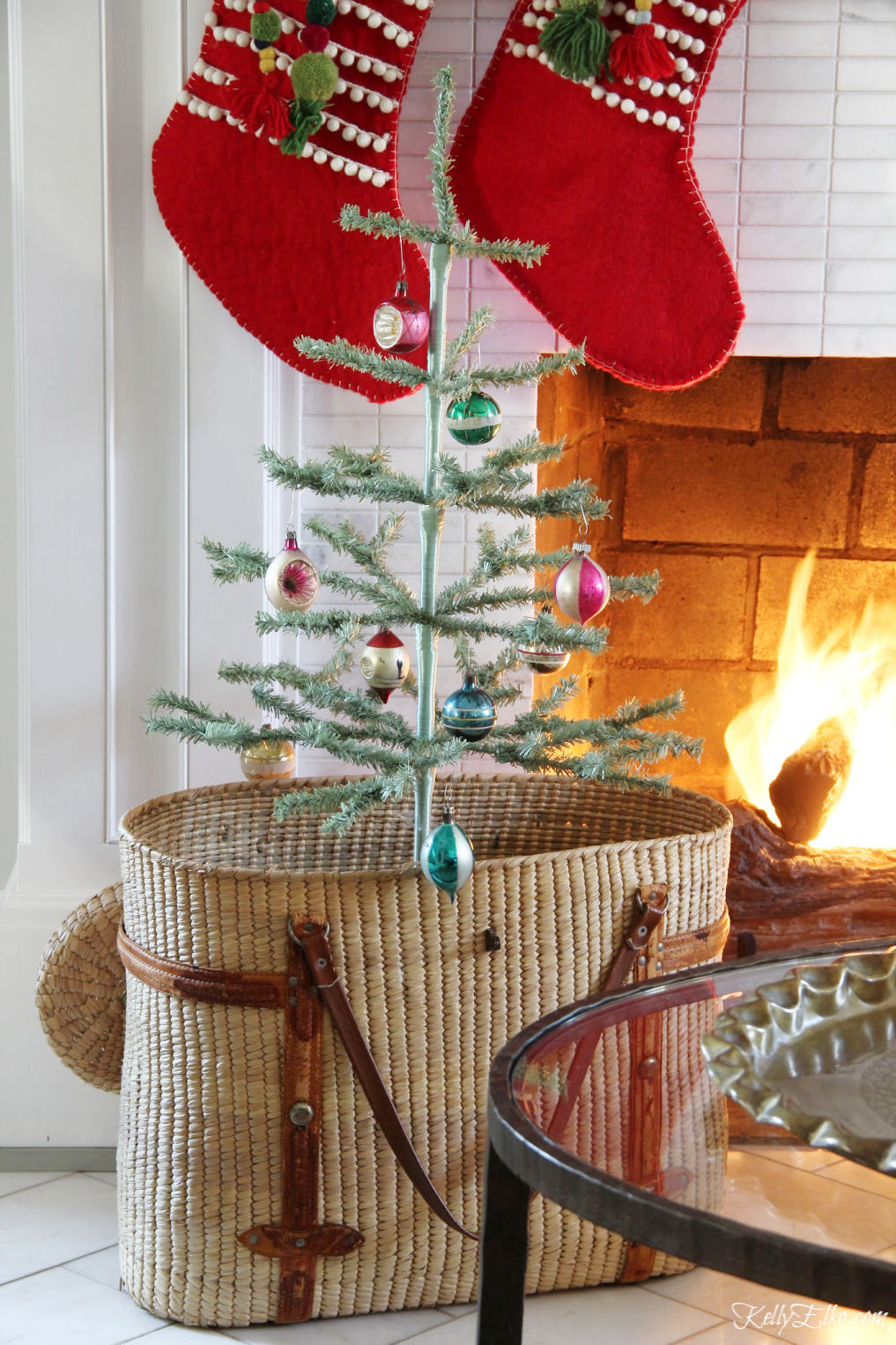 Beautiful Christmas mantel with feather trees in a basket and red stockings kellyelko.com #christmas #christmasdecor #christmasdecorating #christmashome #christmastour #diychristmas #christmasideas #christmasmantel #christmastree #christmasornaments #vintagechristmas #farmhousechristmas #colorfulchristmas #creativechristmas #kellyelko