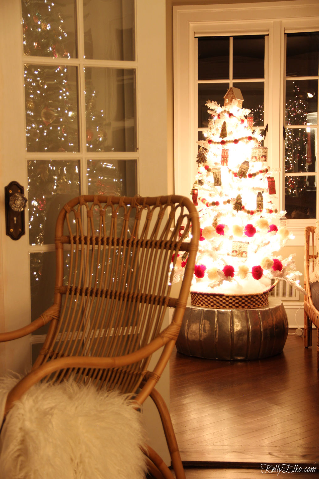 Tour this Christmas home by the glowing lights at night with a beautiful white tree kellyelko.com #christmasdecor #christmastree #whitetree #whitechristmastree #christmasglow #christmaslights #farmhousechristmas #farmhousedecor #rattanfurniture #kellyelko