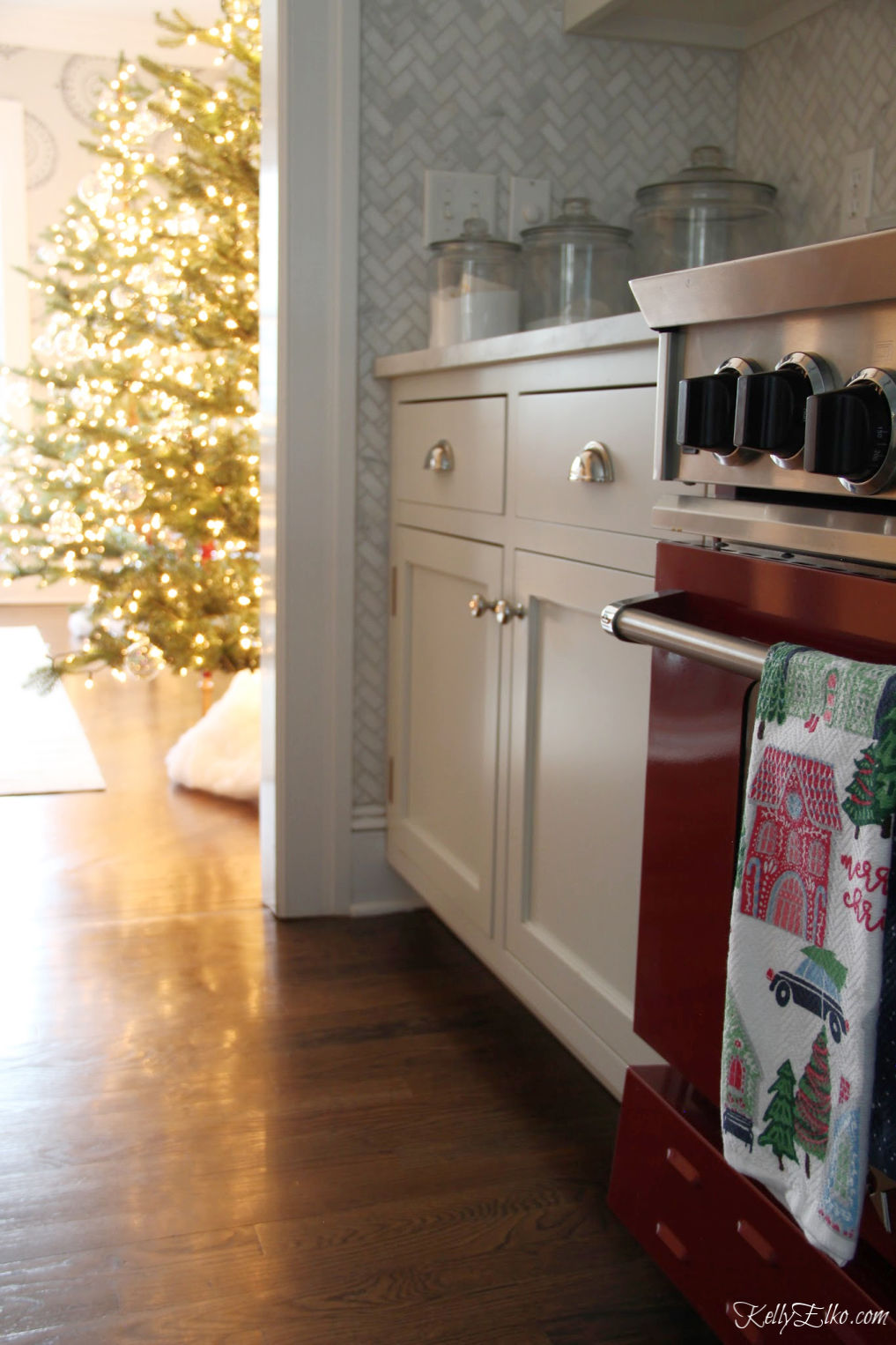 Christmas Home Tour - love the red stove and the twinkling Christmas trees kellyelko.com #christmas #christmasdecor #christmasdecorating #christmashome #christmastour #diychristmas #christmasideas #christmasmantel #christmastree #christmasornaments #vintagechristmas #farmhousechristmas #colorfulchristmas #creativechristmas #kellyelko #christmaskitchen #redstove 