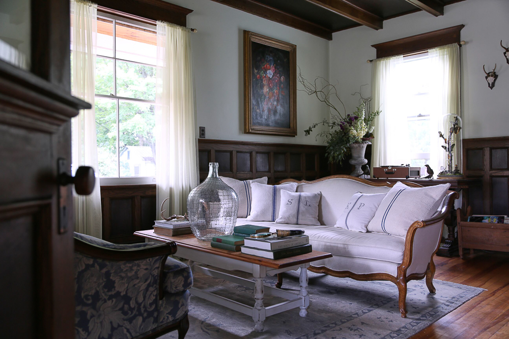 A pair of settees are covered in coordinating fabrics and grain sack pillows with initials kellyelko.com #antiques #farmhouse #farmhousedecor #antiquefurniture #art #countryliving #oldhouse #housetour 