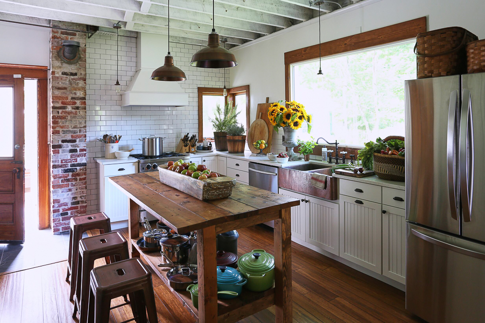 Charming farmhouse kitchen with subway tile backsplash, copper farmhouse sink, wood table island and exposed brick kellyelko.com #kitchen #kitchendecor #farmhouse #farmhousedecor #farmhousekitchen #countrykitchen #countryliving #kitchenisland #rustickitchen #oldhouse #housetour 