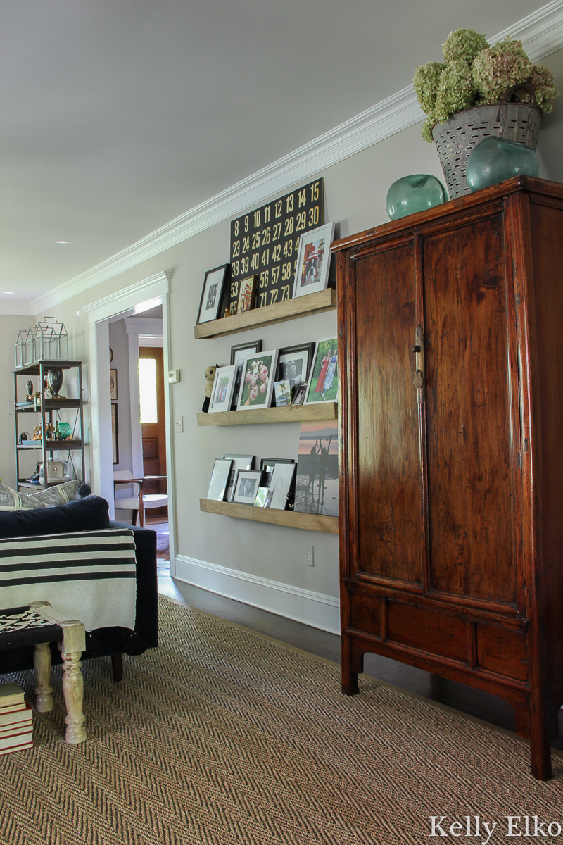 Eclectic living room with picture ledge family photo wall and antique armoire kellyelko.com #armoire #antiquedecor #antiquefurniture #bohodecor #eclecticdecor #pictureledge #gallerywall #livingroomdecor