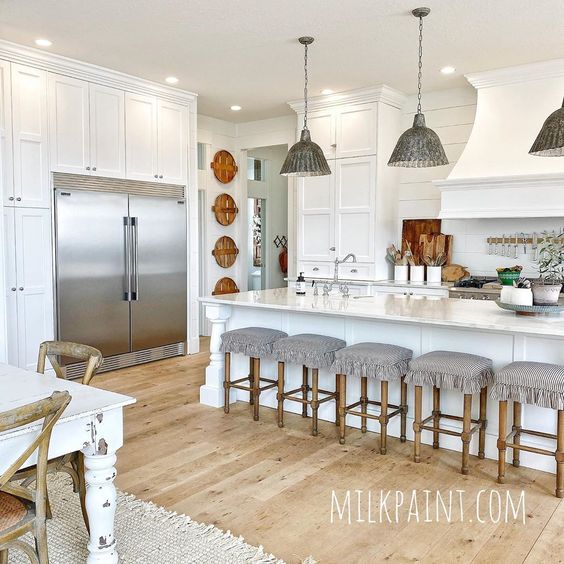 Love this beautiful farmhouse white kitchen with galvanized metal lighting and basket wall art kellyelko.com #farmhouse #farmhosuekitchen #farmhousedecor #whitekitchen #kitchenlighting #kitchenisland #vintagedecor #kitchenstools #shiplap