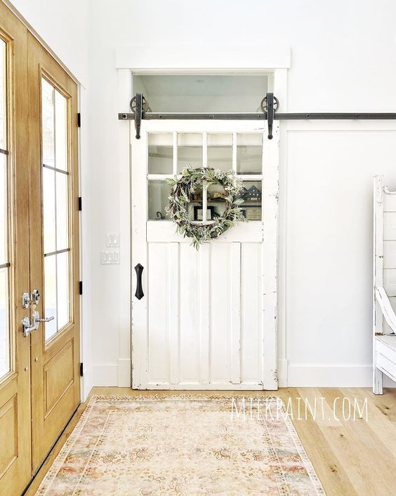 Love the rolling barn door in the entry of this farmhouse kellyelko.com #farmhouse #farmhousedecor #barndoor #rollingbarndoor #rusticdecor #fixerupperstyle #fixerupper #neutraldecor #vintagedecor 