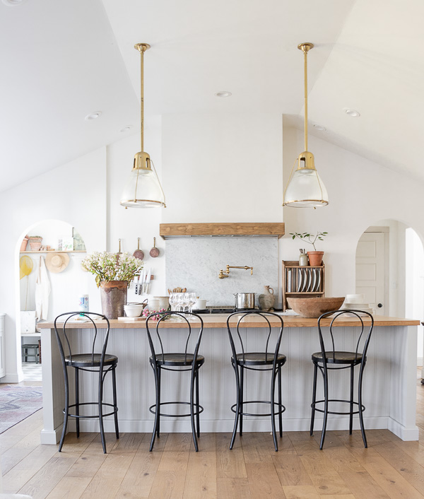 Eclectic Home Tour Seeking Lavender Lane - tour this rancher turned farmhouse with touches of European flair. Love this open concept kitchen with classic black bistro chairs and brass lighting #kitchen #whitekitchen #farmhousekitchen #farmhousedecor #eclectickitchen #kitchenlighting #brasslighting #kitchenrenovation #hometour #housetour #interiordesign 