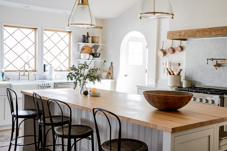 European farmhouse kitchen with a mix of marble and butcher block counters and brass accents and lighting #farmhouse #farmhousekitchen #kitchen #whitekitchen #butcherblockcounter #kitchendecor #kitchenreno #kitchenlighting #barstools