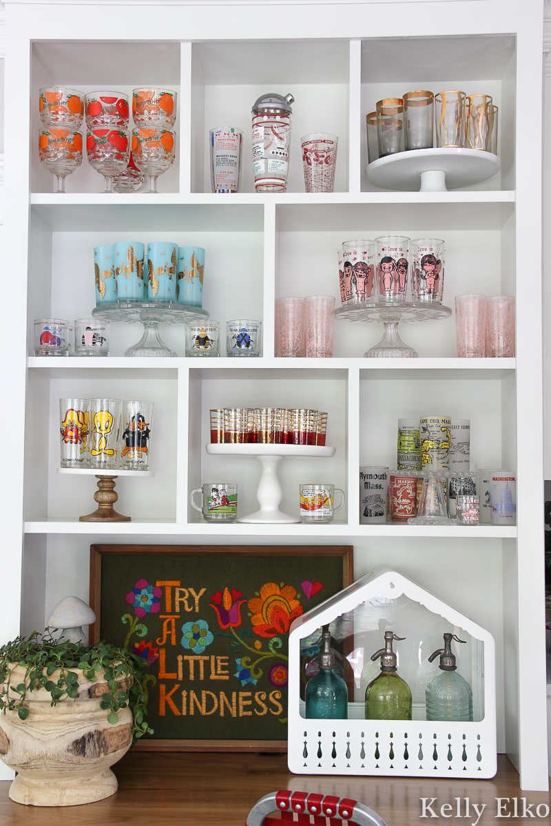 Love this colorful vintage drinking glass display in this white kitchen kellyelko.com #vintageglass #vintageglasses #drinkingglasses #vintagedrinkingglass #collectibles #collections #collect #collector #kitchendecor #vintagedecor #colorfuldecor #thrifted #vintagemodern #shelfie #kellyelko #kitchen 