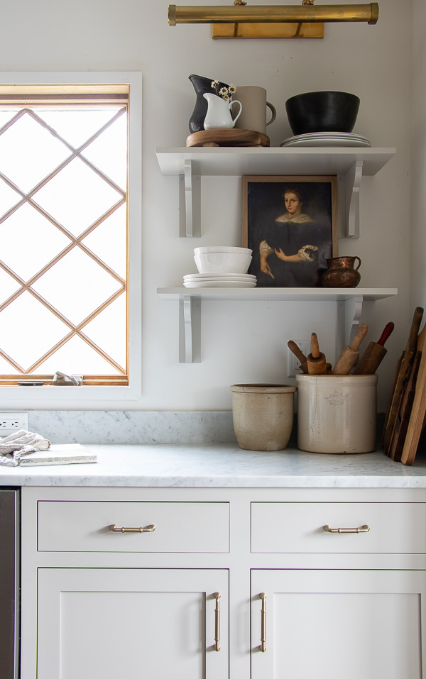 Picture lighting looks great in a kitchen for highlighting art and collections #kitchen #farmhousekitchen #kitchendecor #portrait #picturelighting #brass #kitchenshelves #vintagedecor 