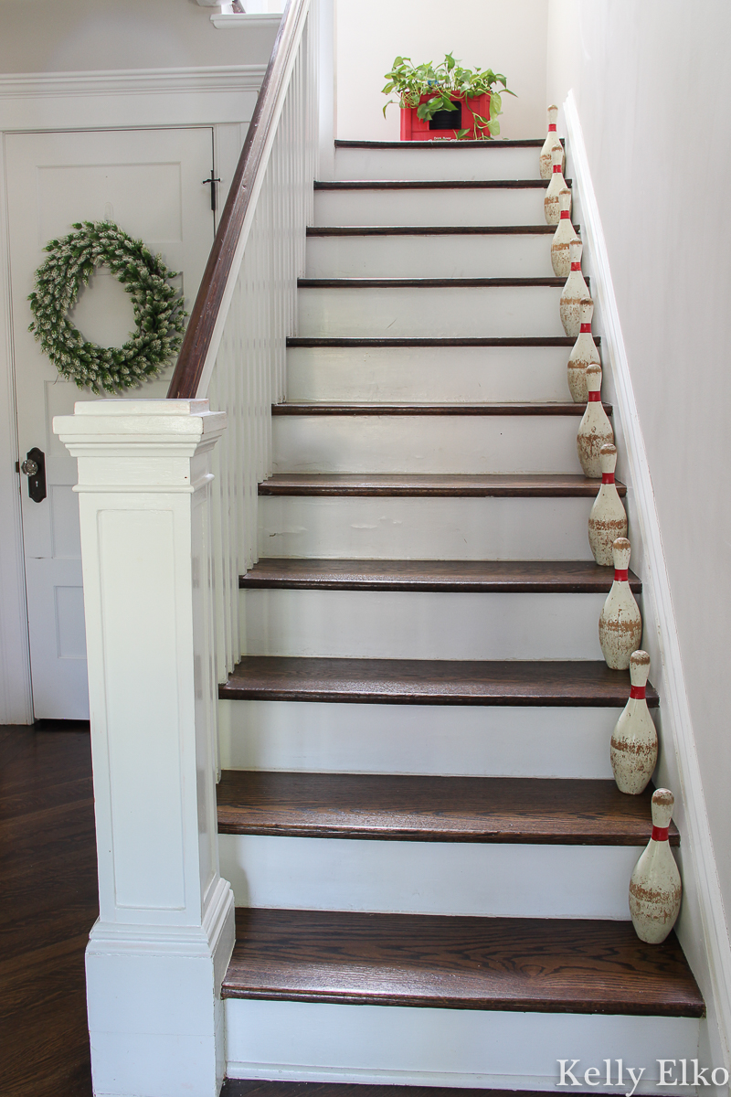 Love the vintage lawn bowling pin set on the staircase of this farmhouse foyer kellyelko.com #vintage #vintagedecor #bowlingpins #farmhouse #farmhousedecor #farmhouseentry #foyer #foyerdecor #staircasedecor #graypaint #neutraldecor #summerdecor #eclecticdecor #collections #collector #thrifted #houseplants #plantlady