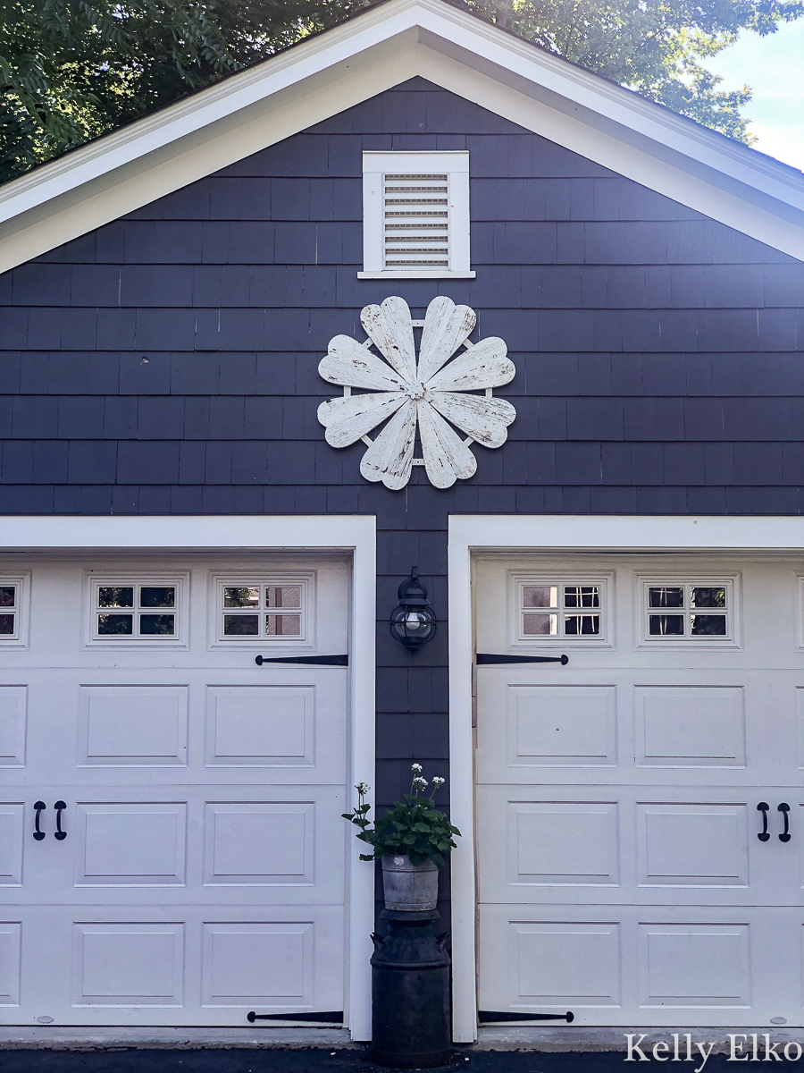 Love this giant barn wood flower hung on the garage for instant curb appeal kellyelko.com #garage #outdoordecor #farmhousedecor #farmhousestyle #whiteflower #curbappeal #halenavy #bluepaint #paintcolors #exteriorpaintcolors