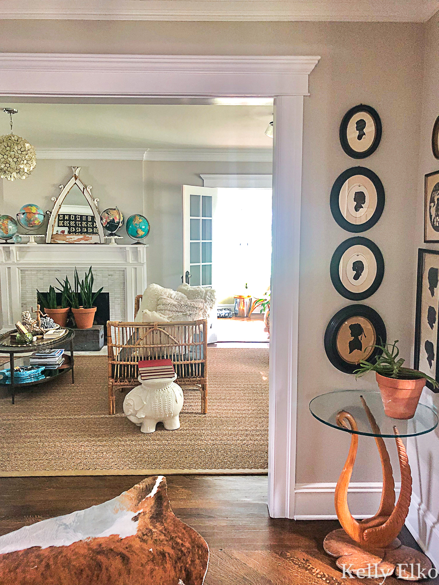 Love this eclectic living room with so many unique vintage finds kellyelko.com #vintagedecor #vintagefurniture #eclecticdecor #livingroomdecor #globes #rattan #collections 