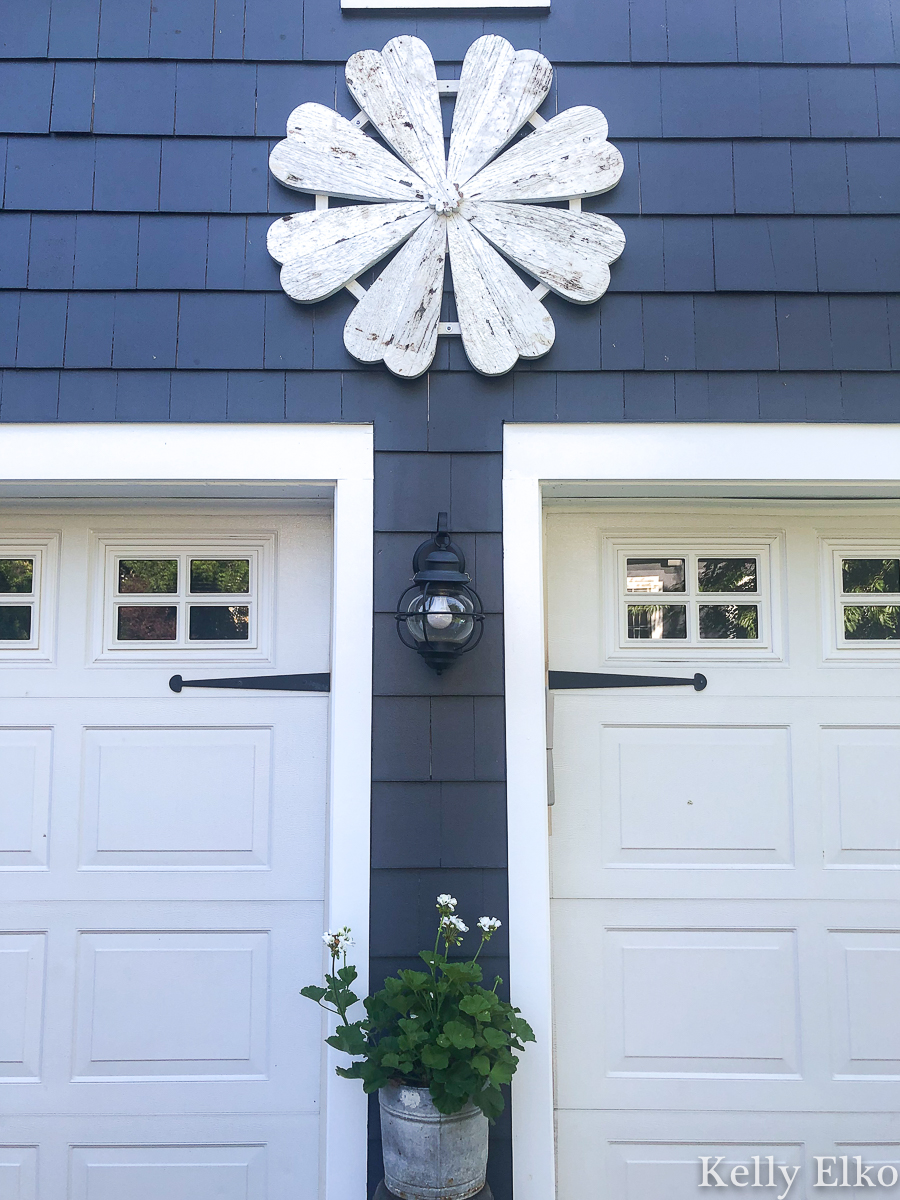 Love this giant barn wood flower hung on the garage for instant curb appeal kellyelko.com #garage #outdoordecor #farmhousedecor #farmhousestyle #whiteflower #curbappeal #halenavy #bluepaint #paintcolors #exteriorpaintcolors