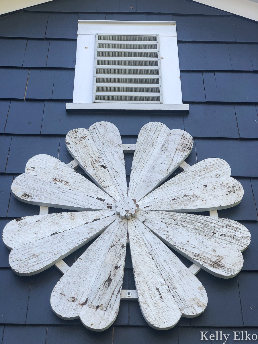 Love this giant barn wood flower hung on the outside of her house for instant curb appeal kellyelko.com #garage #outdoordecor #farmhousedecor #farmhousestyle #whiteflower #curbappeal #halenavy #bluepaint #paintcolors #exteriorpaintcolors
