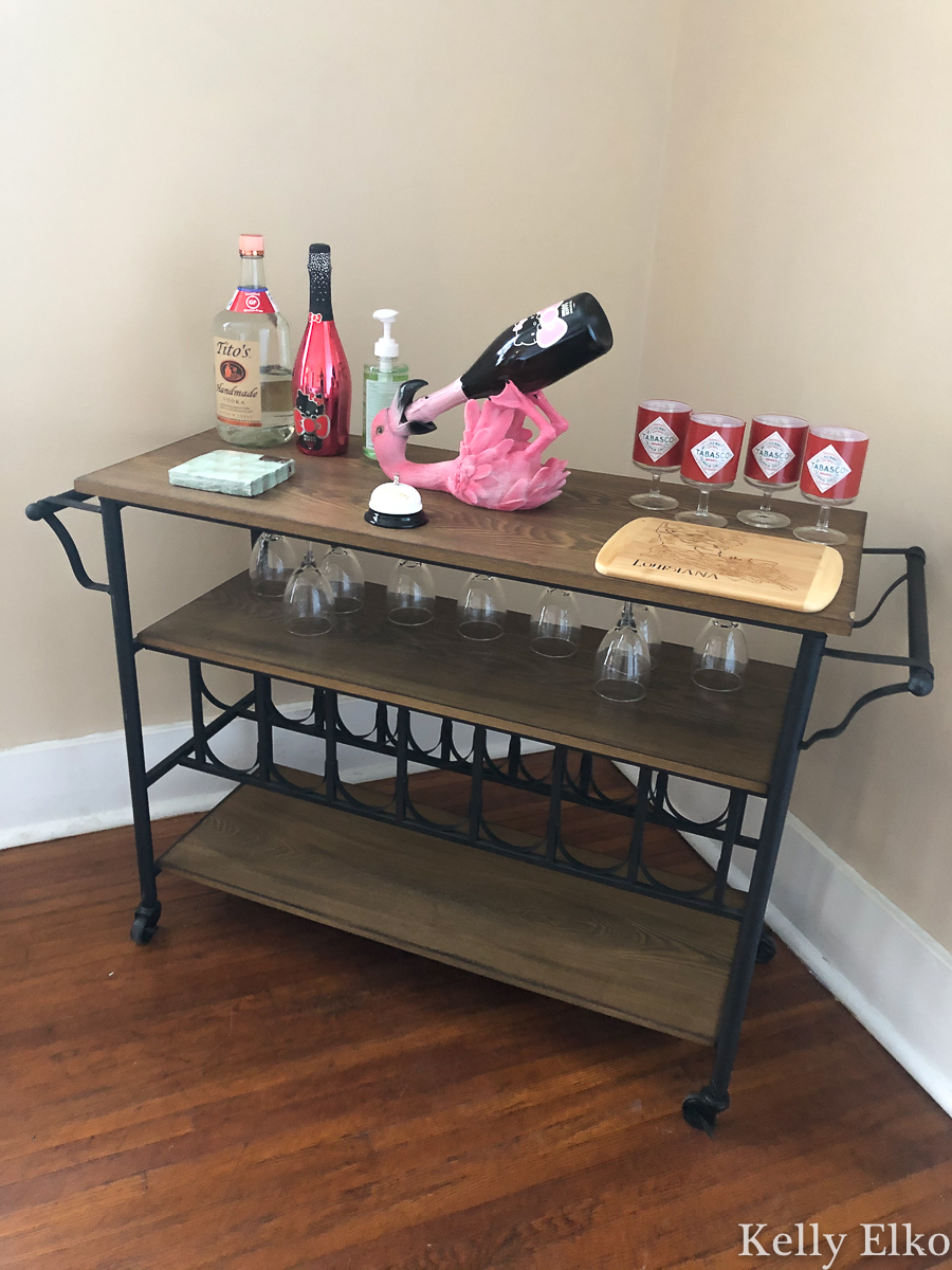 Love this bar cart with the weird flamingo bottle holder kellyelko.com #barcart #pinkflamingo #wine #apartmentdecor 