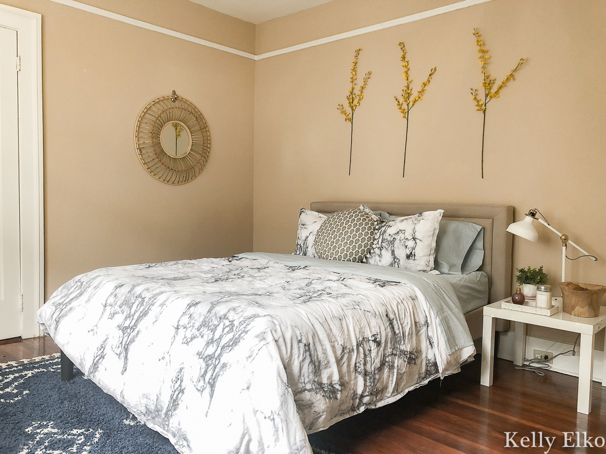 How to furnish a college apartment on a budget - love the idea of hanging flowering branches on the wall kellyelko.com #bedroom #bedroomdecor #floralart #apartmentdecor #apartmentfurniture #inexpensivedecor #budgetdecor #budgetart #platformbed #eclecticbedroom #thriftydecorideas 