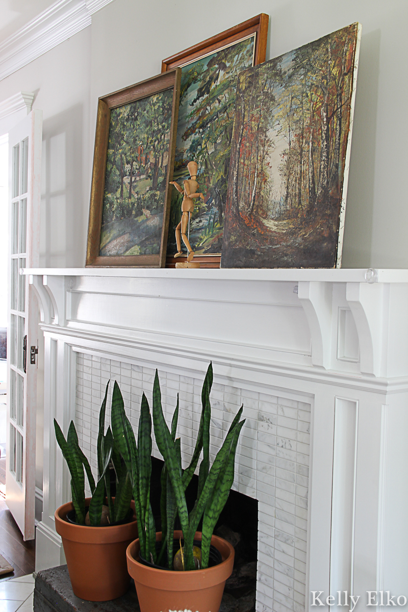 Love this fall mantel with a trio of vintage landscape paintings and snake plants covering the fireplace opening kellyelko.com #vintagedecor #vintagepaintings #vintageart #vintagelandscape #falldecor #fallmantel #houseplants #manteldecor #fallhometour 