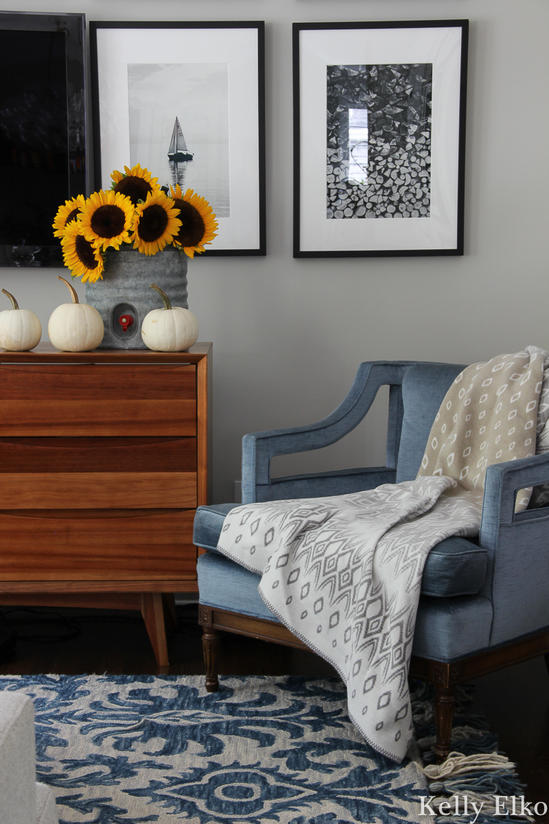 Fall decorating is all about adding texture like a tassel rug and cozy throw kellyelko.com #bluedecor #cozydecor #vintagedecor #vintagechair #midcenturydecor #eclecticdecor #sunflowers #pumpkindecor #whitepumpkins 