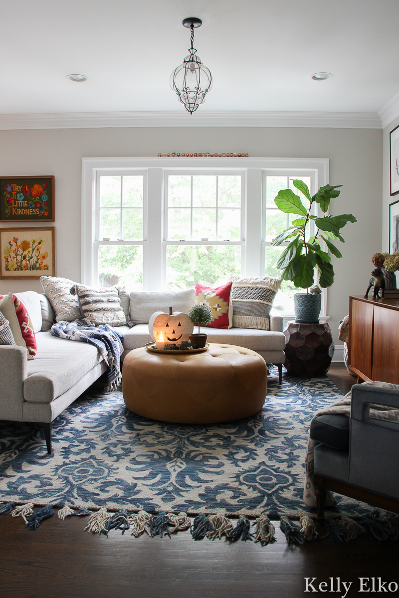 Eclectic and colorful fall family room with beautiful vintage finds kellyelko.com #cozy #cozyspaces #eclecticdecor #colorfuldecor #familyroomdecor #falldecor #vintagedecor #fiddleleaffig #pumpkindecor #crewelart #sectionalsofa #loloi