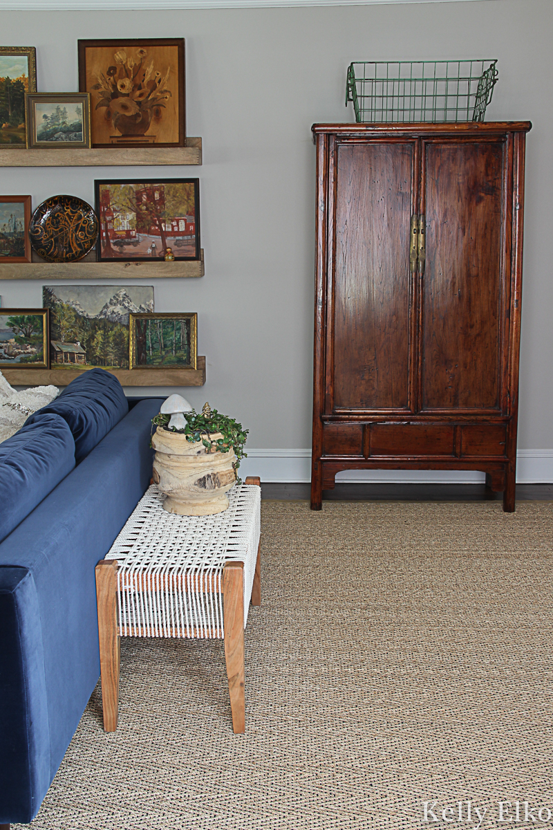 Beautiful fall living room displaying so many unique vintage finds like the collection of vintage landscape paintings kellyelko.com #armoire #vintagedecor #bohodecor #eclecticdecor #falldecor 