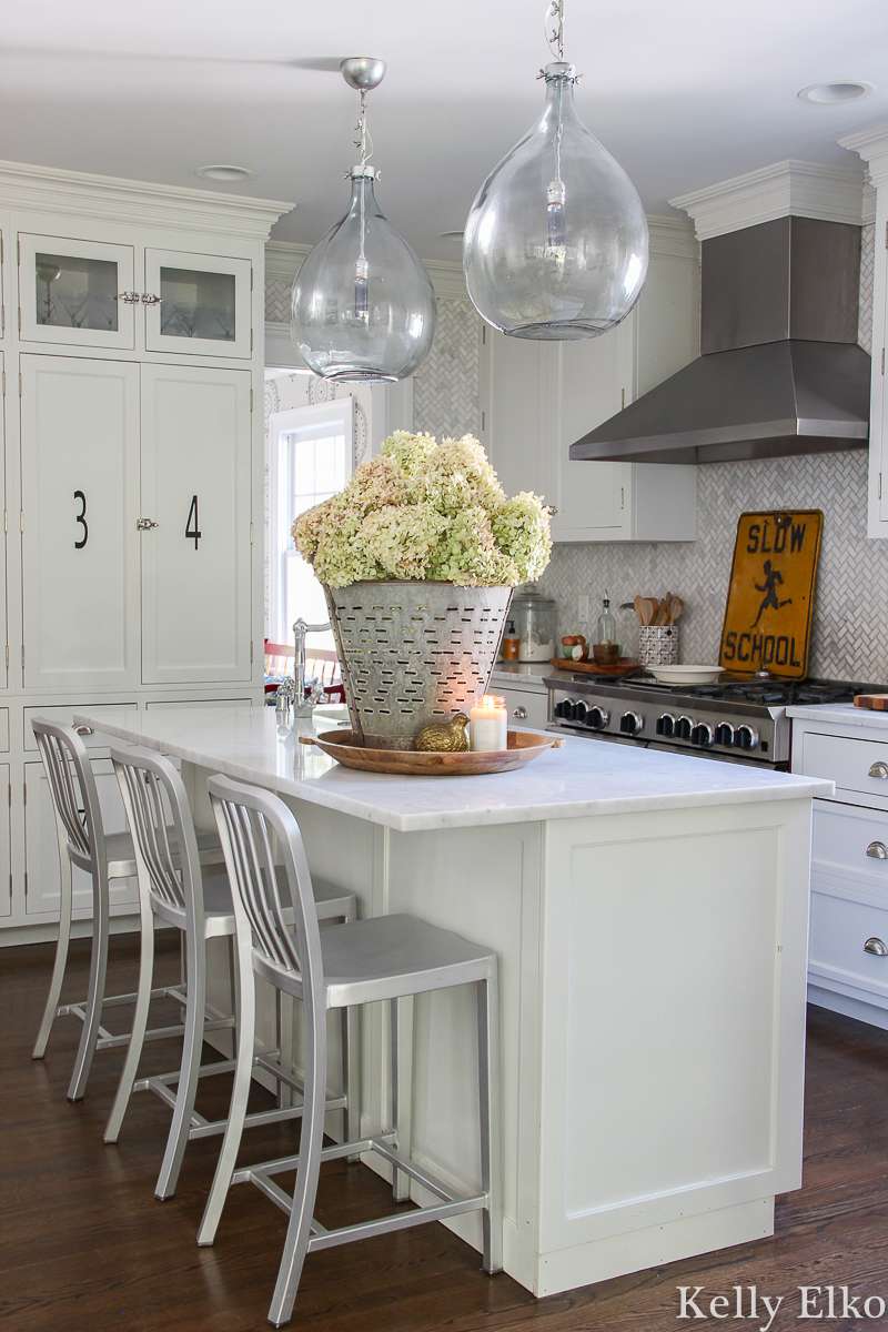 Love this beautiful white farmhouse kitchen with a huge vase of hydrangeas kellyelko.com 