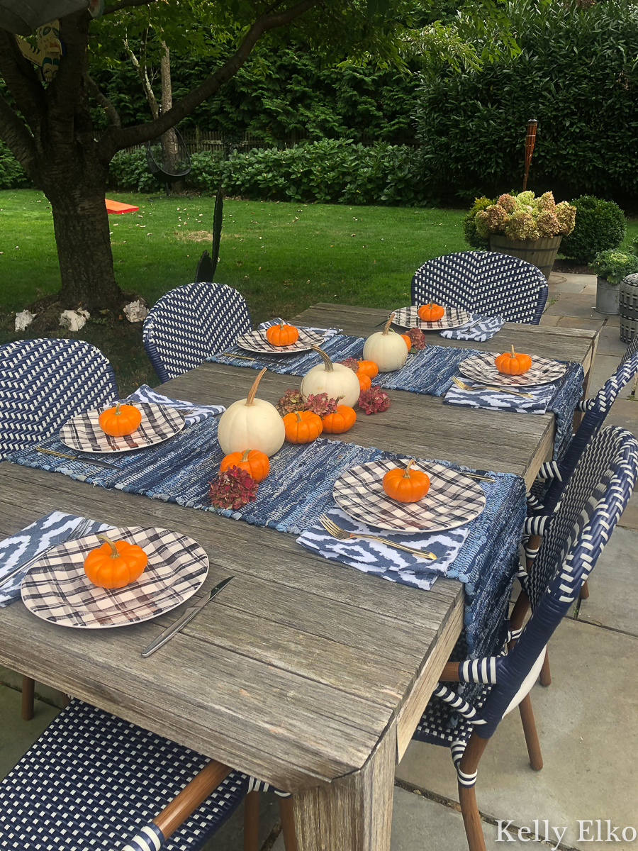 Fall Patio Tour - love this fall table setting with white and orange pumpkins kellyelko.com #fall #fallpatio #falldecor #falltable #fallcenterpiece #falldecorating #pumpkindecor #farmhousedecor #farmhousefall #eclecticdecor #tablesetting #outdoordinner #alfresco