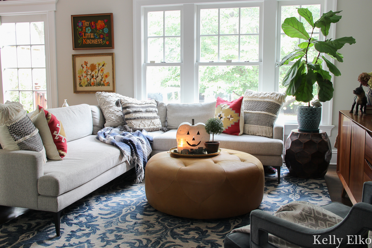 Eclectic and colorful fall family room with beautiful vintage finds kellyelko.com #cozy #cozyspaces #eclecticdecor #colorfuldecor #familyroomdecor #falldecor #vintagedecor #fiddleleaffig #pumpkindecor #crewelart #sectionalsofa #loloi #crewel #ottoman #article 