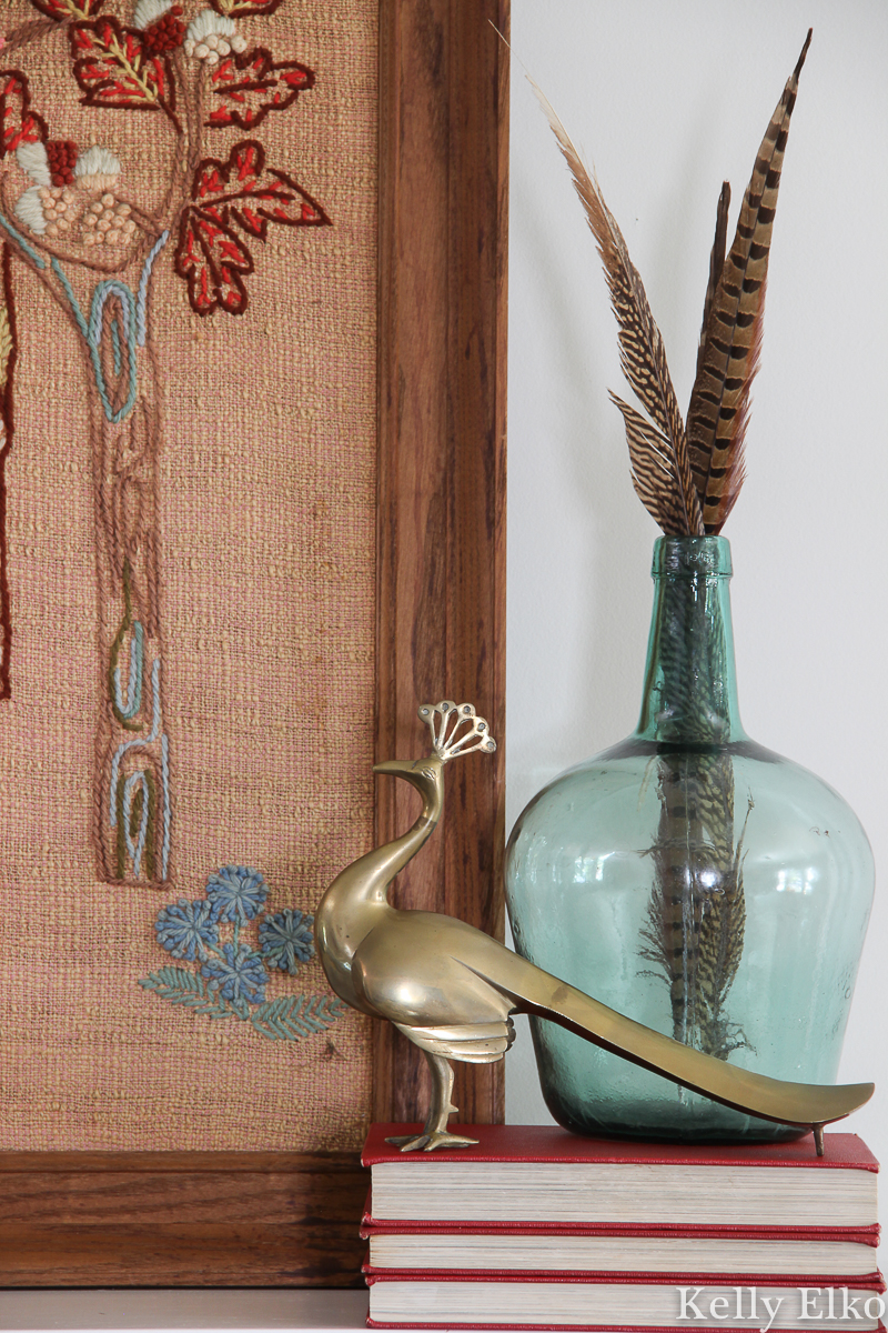 Vintage mantel with brass peacock, crewel art and feathers in glass kellyelko.com #vintagedecor #falldecor #fallmantel #brass #vintagebrass #peacock #eclecticdecor 