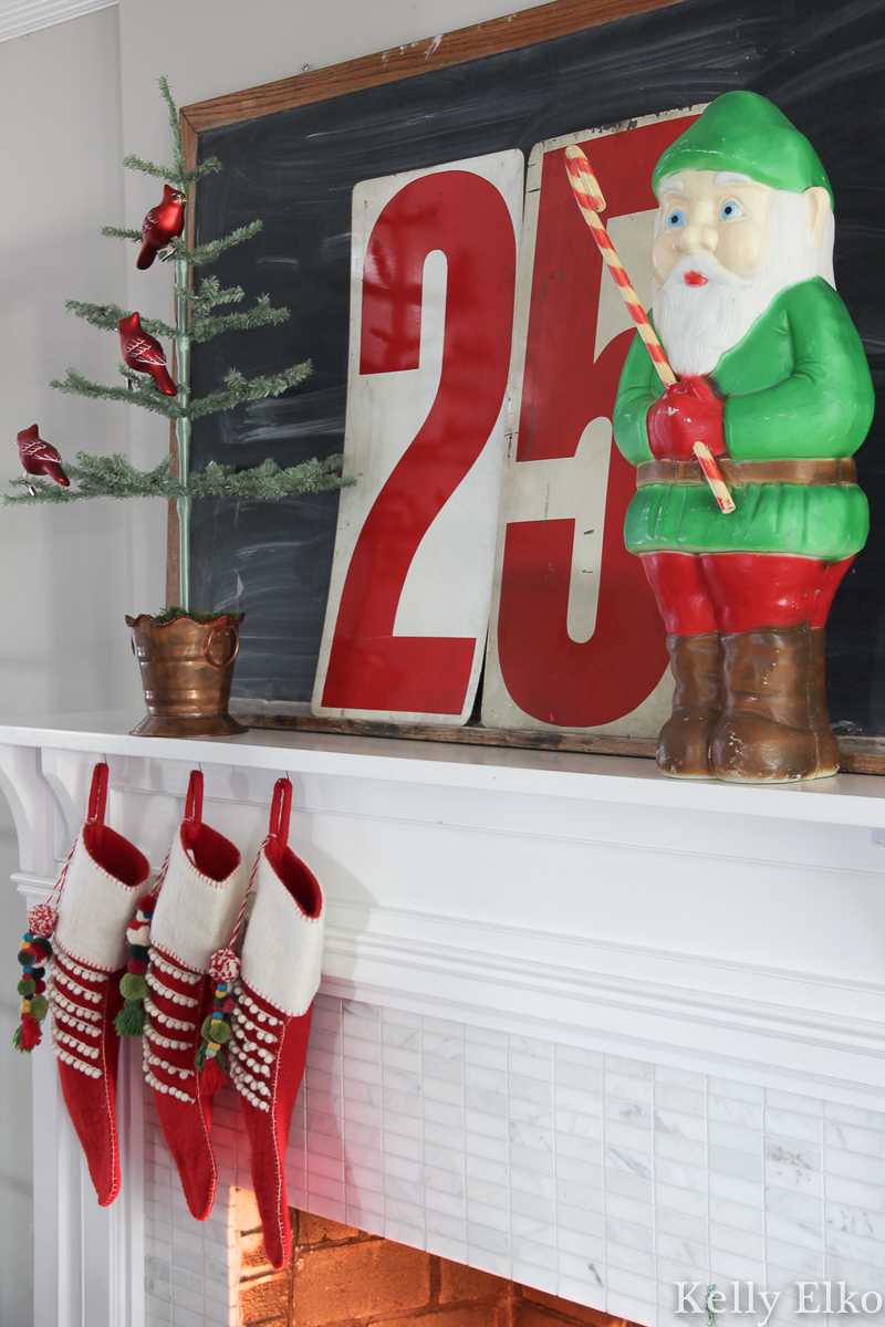Love this retro Christmas mantel with elf blow mold kellyelko.com #christmasdecor #christmasmantel #vintagechristmas #retrochristmas #blowmold #christmasblowmold #elfblowmold #christmasstockings #feathertree #christmashome #christmashometour 