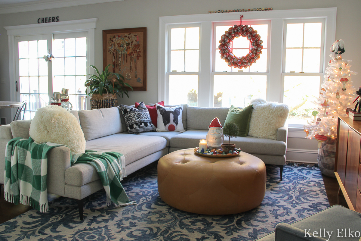 Festive Christmas decor and I love the dog Rudolph pillow! kellyelko.com #christmasdecor #christmasfamilyroom #christmaswreath #colorfulchristmas #whitechristmastree #plaidthrow #christmaspillows #sectionalsofa #loloirug