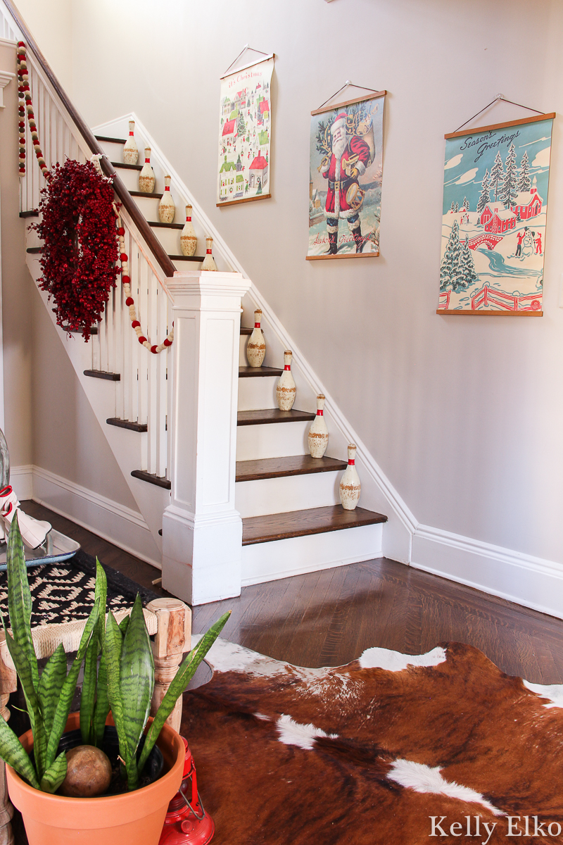 Affordable Christmas art - love this foyer decked out for the holidays with retro inspired art kellyelko.com #christmas #christmasdecor #christmasfoyer #farmhousechristmas #retrochristmas #vintagechristmas #christmasart #santa #vintagedecor #foyer #foyerdecor #staircaseart 