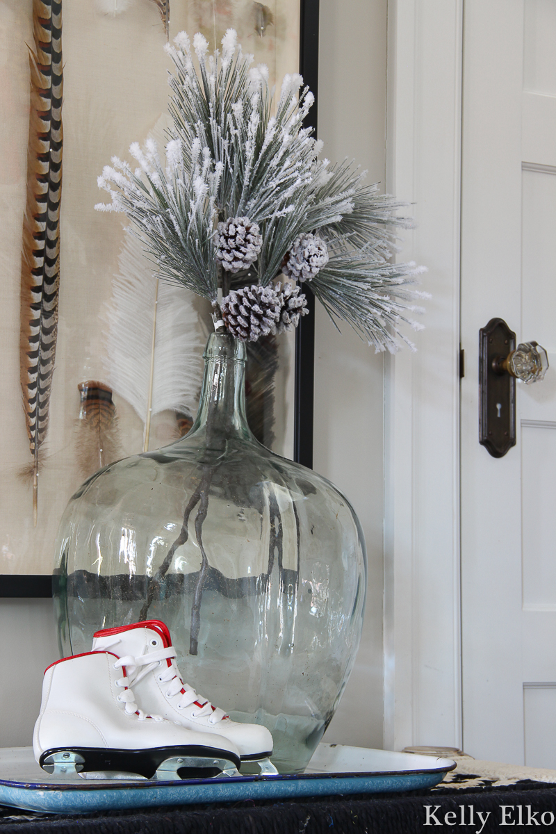 Love this simple sprig of greenery in a big glass jar kellyelko.com #christmasdecor #farmhousechristmas #iceskates #vintagechristmas 